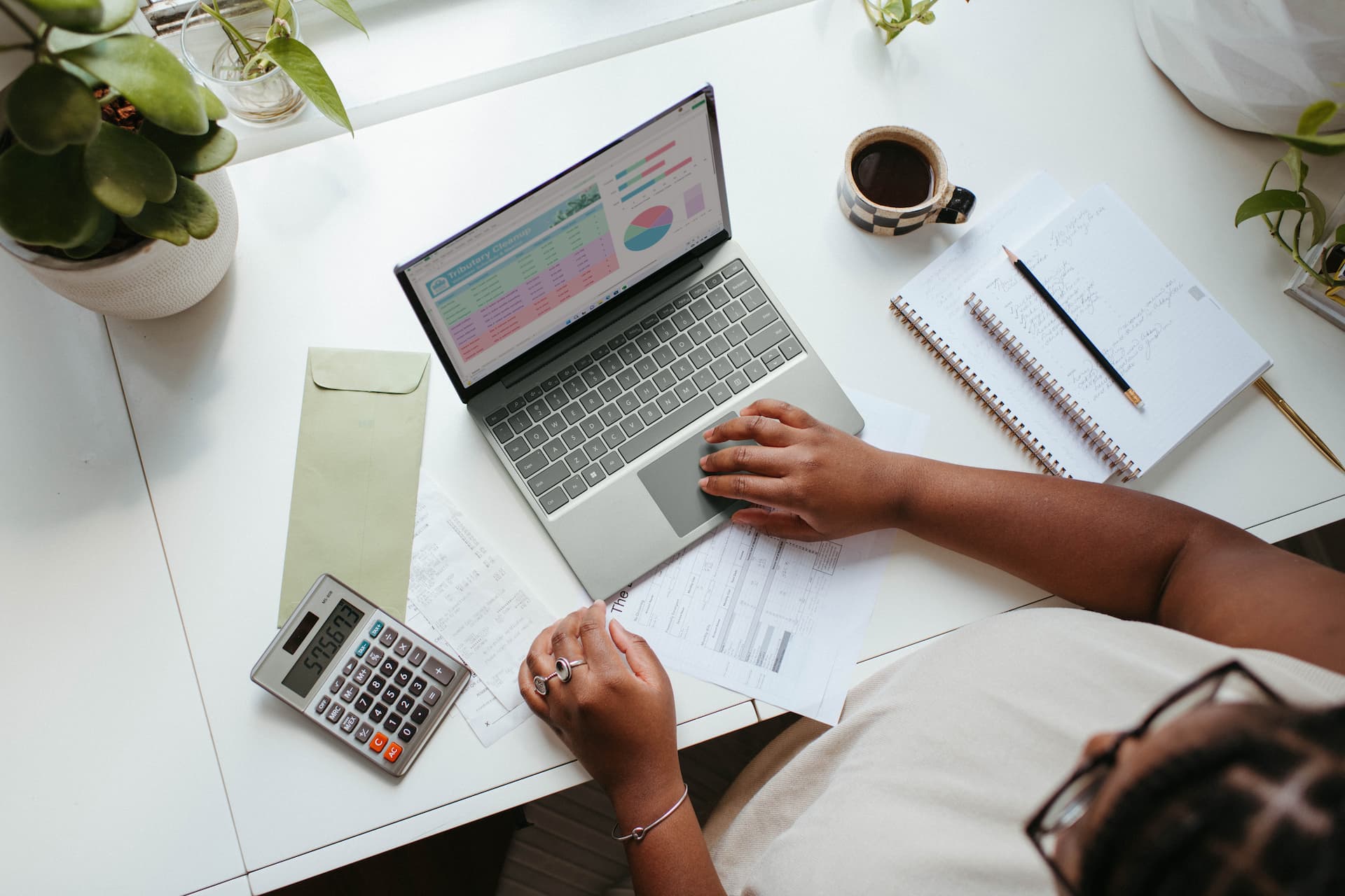 Completing an online business transaction on a laptop, with calculator and financial details on table.