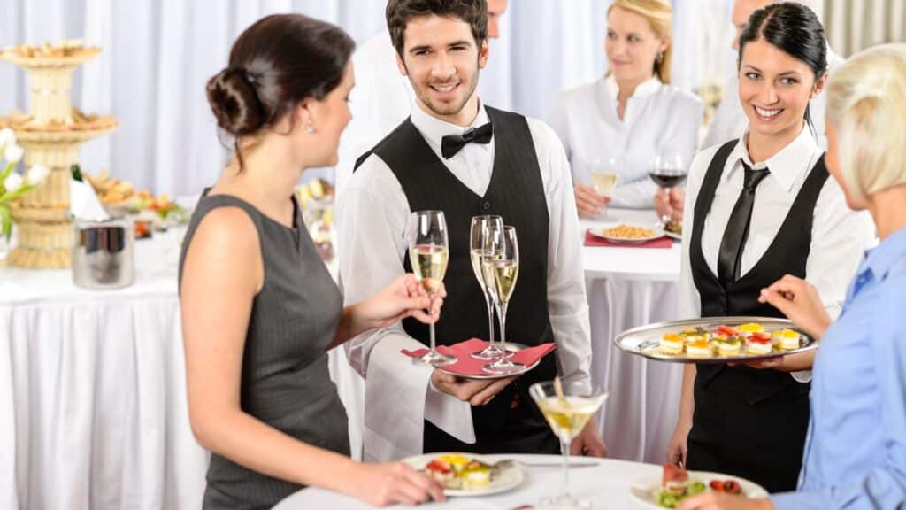 Hotel function room with waiters servicing alcoholic drinks.