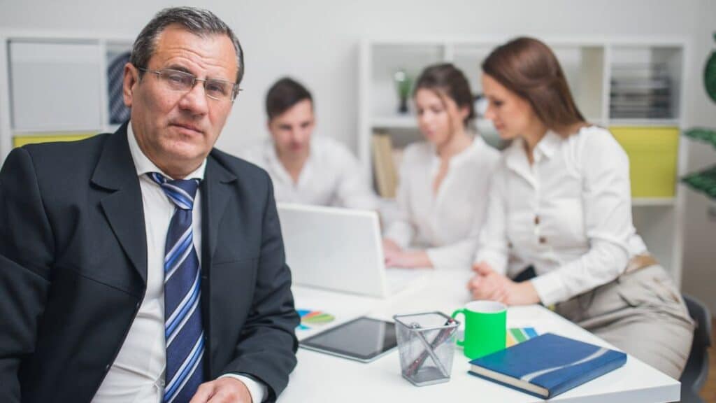 Company Director sitting with his employees in the office.