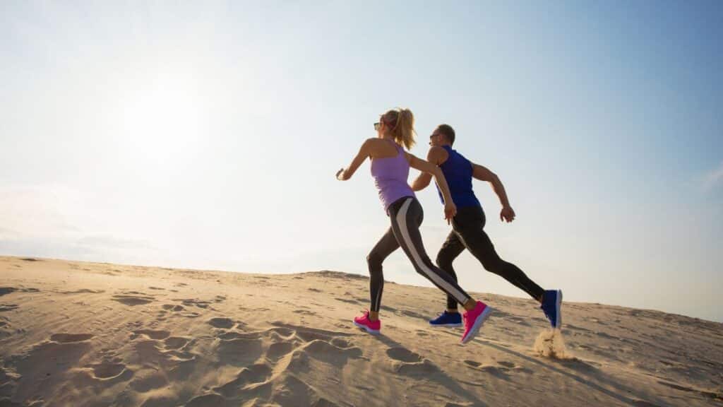 Woman and man discussing enduring guardian as they run up a sand dune.