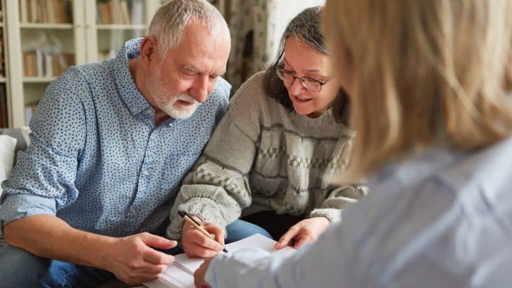 Married couple discussing power of attorney and signing documents with their lawyer.