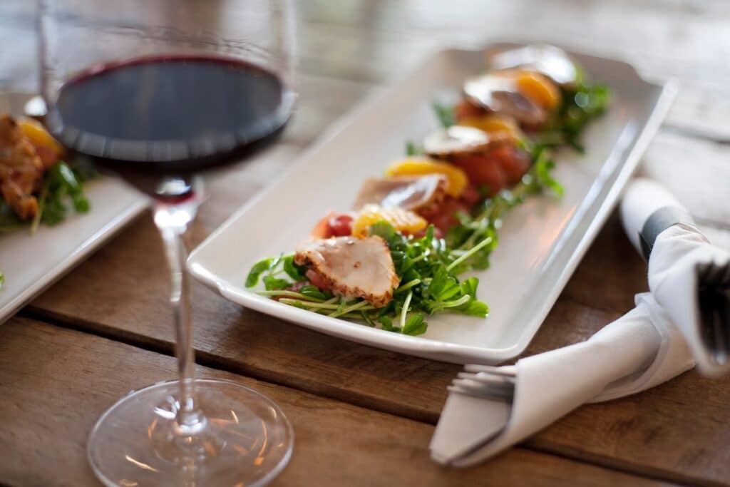 Professionally plated food and red wine on a restaurant dining table.