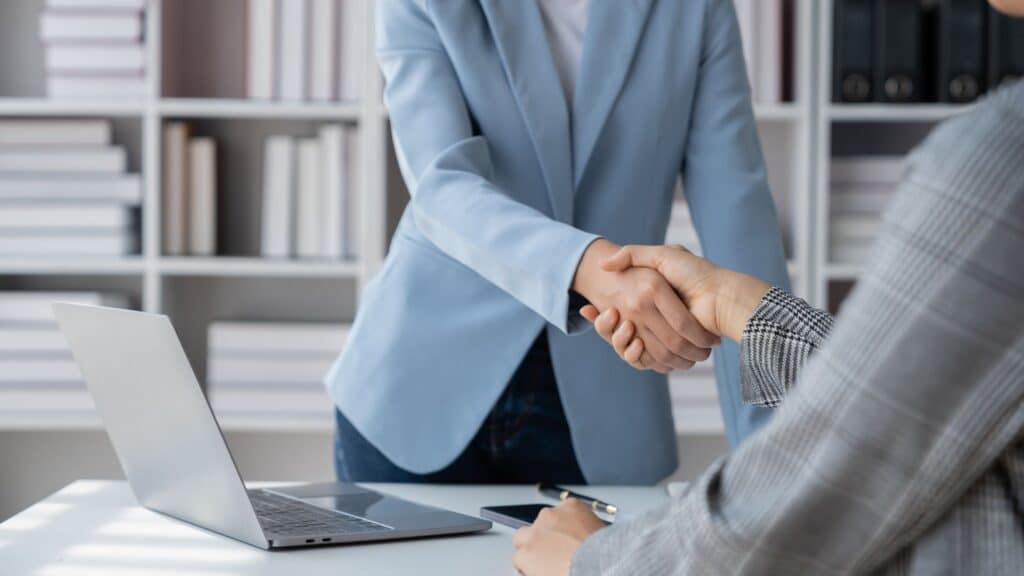 Commercial property lawyers shaking hands while discussing a joint venture agreement.