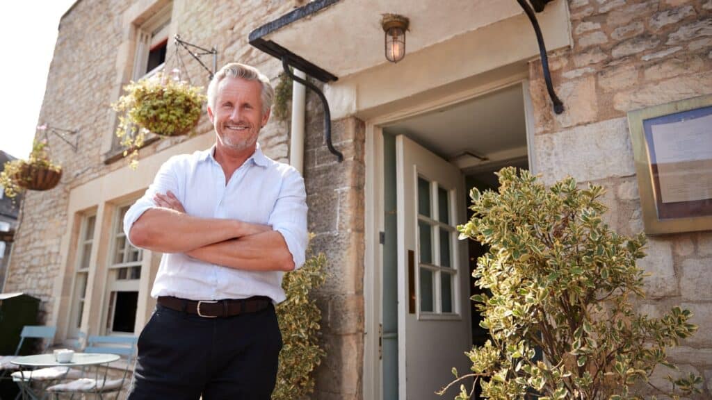 Landlord of business premises standing outside the front door.